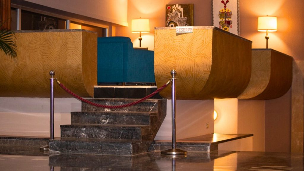 Aménagement d’espace VIP avec fauteuils, parement mural texturé et éclairage indirect – projet Sarakawa Hildawa Home